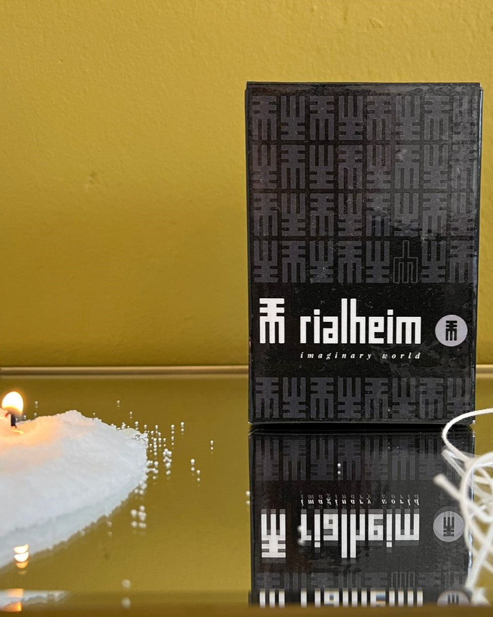 Black box with 'rialheim' branding on a reflective surface with a candle in the background.