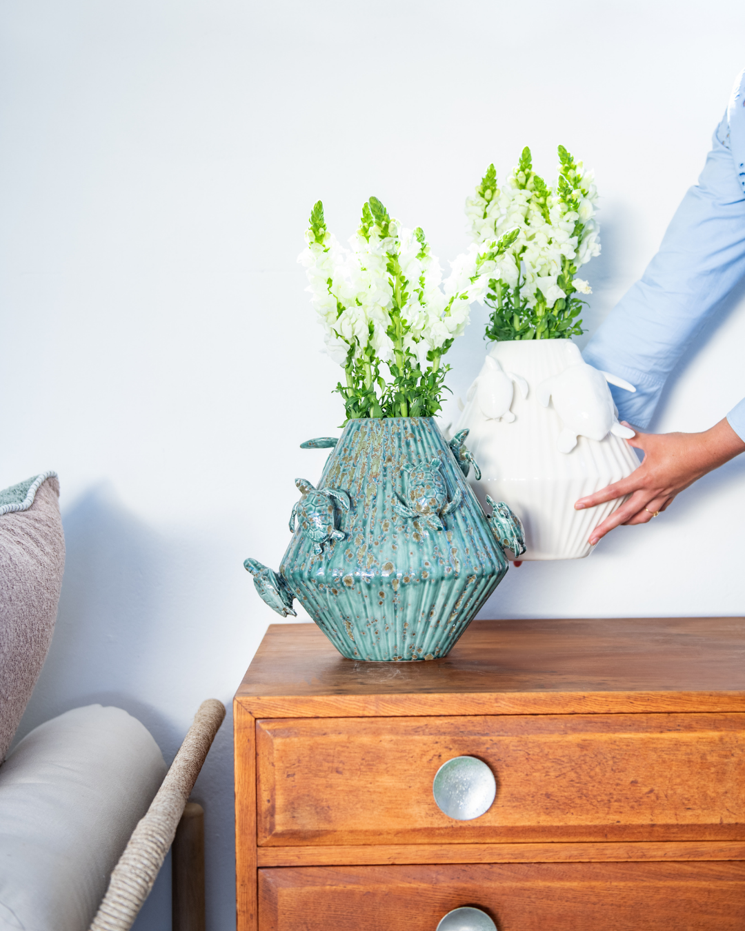 Green & Matt White decorative vase with 3d sea turtles attached on a matching pedestal with a person holding a white version in the background