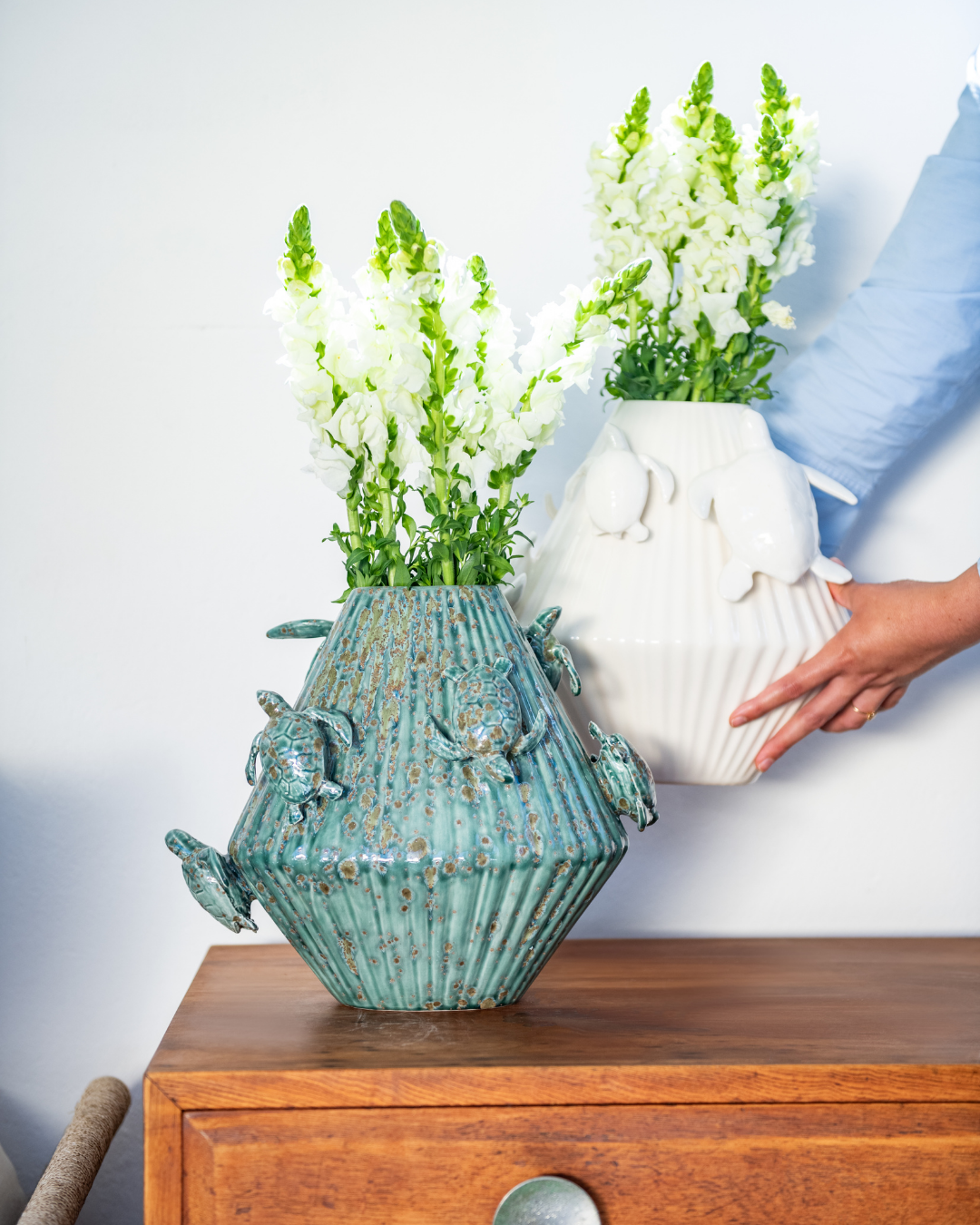 Green & Matt White decorative vase with 3d sea turtles attached on a matching pedestal with a person holding a white version in the background