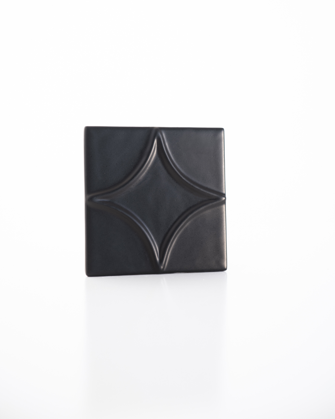 Black decorative tile with a starburst pattern on a white background