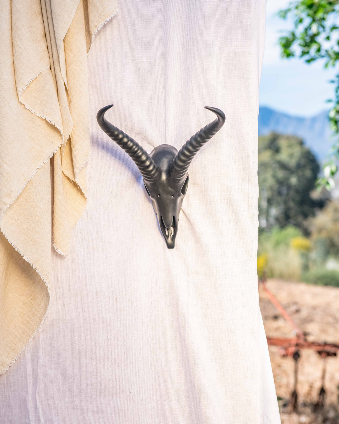 Decorative table settings with Springbok animal horns on brown tablecloths against a white draped backdrop.