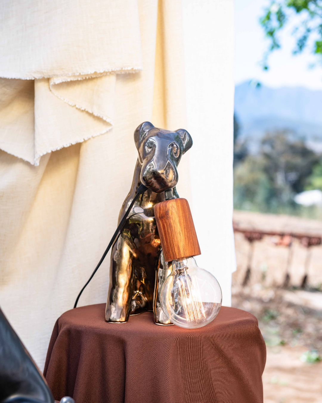 Decorative table settings with Airedale themed lamps on brown cloths against a white curtain backdrop.