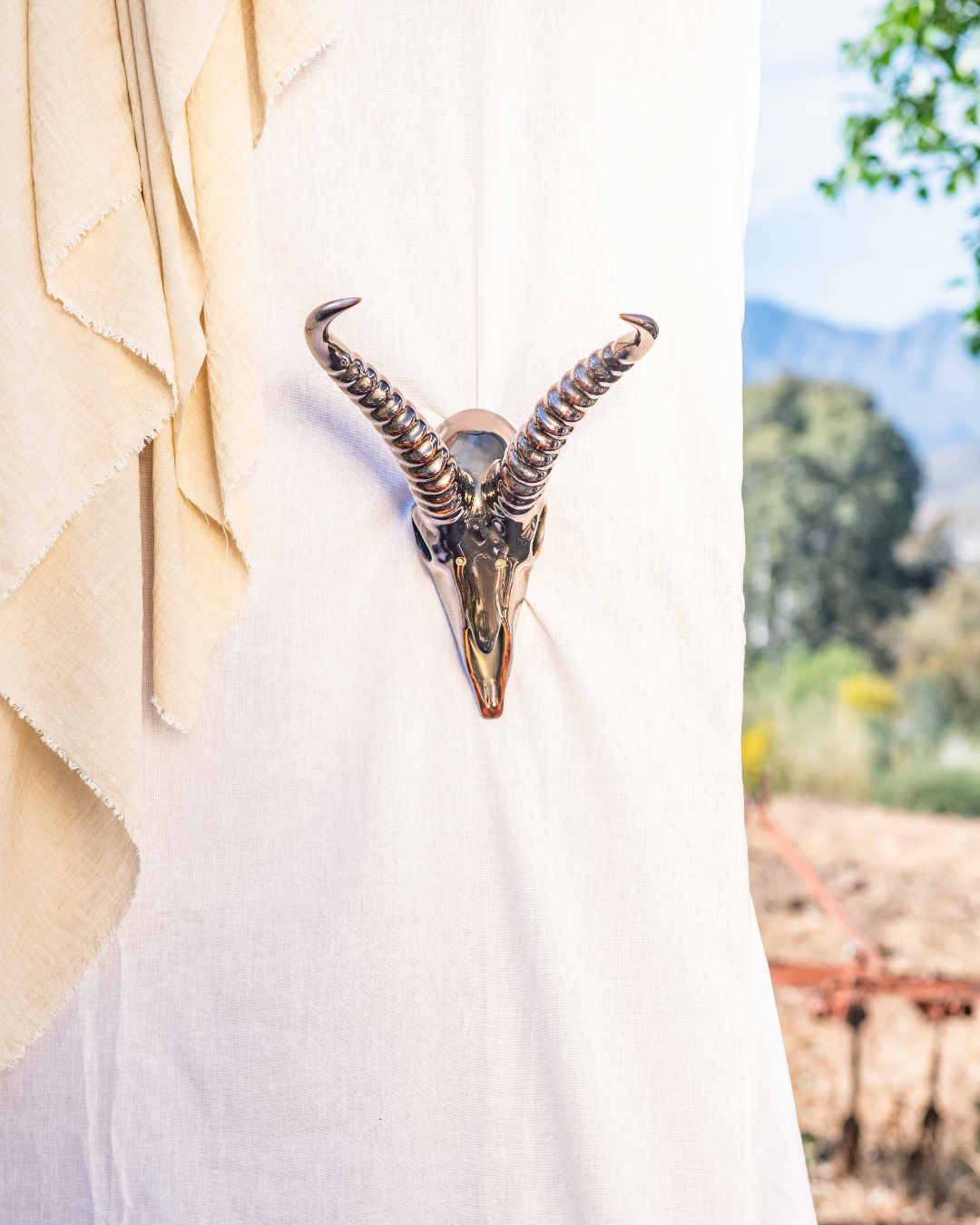 Decorative table settings with Springbok animal horns on brown tablecloths against a white draped backdrop.
