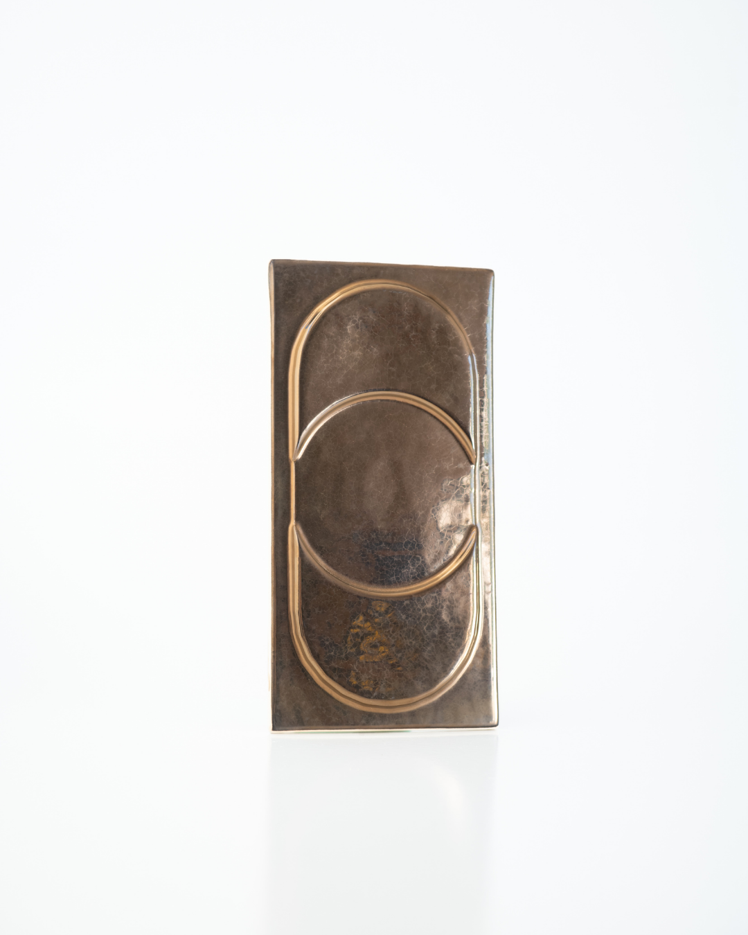 Decorative bronze wall piece with concentric circles on a white background