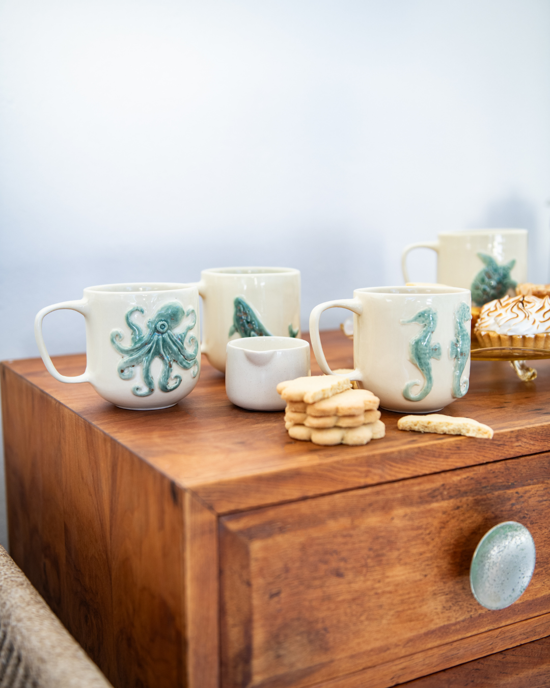 Set of mugs with sea-themed designs on a wooden surface