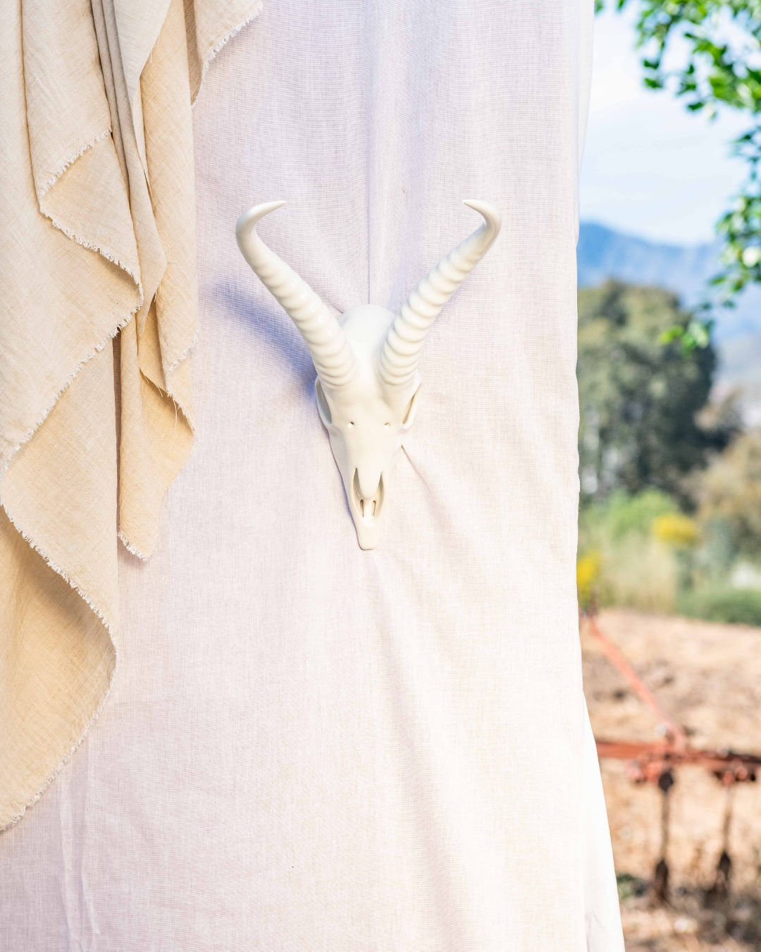 Decorative table settings with Springbok animal horns on brown tablecloths against a white draped backdrop.