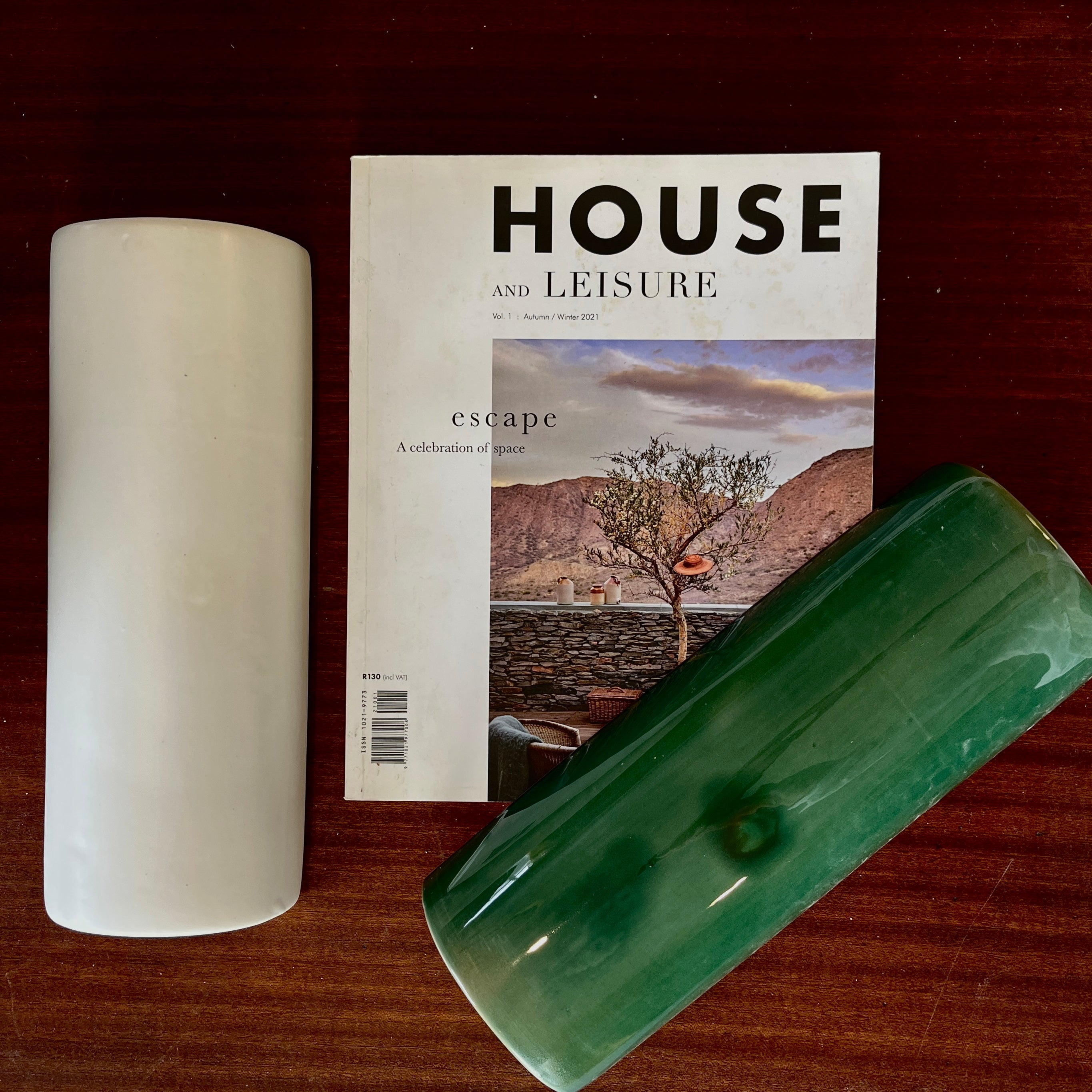 Magazine titled 'House and Leisure' with a candle and green tile on a wooden surface
