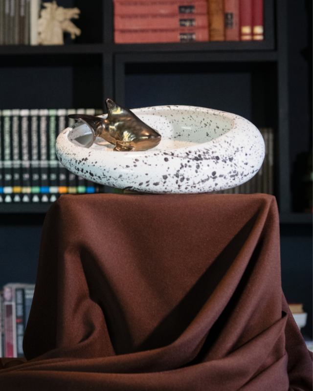 Futuristic KOI fish creature on a white platform with a dark bookshelf background