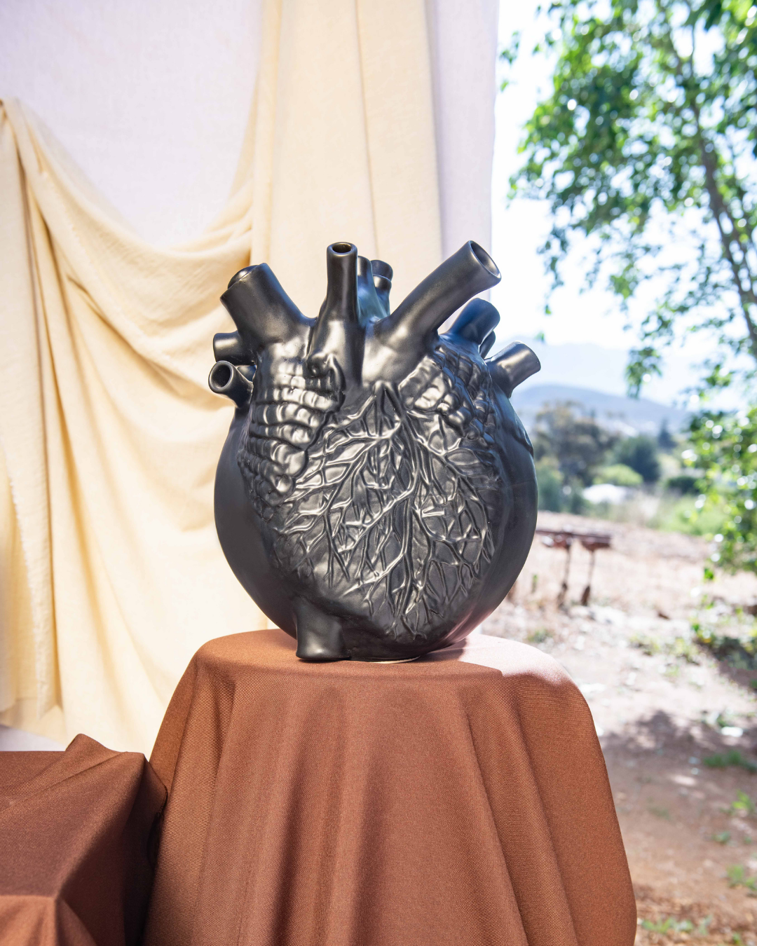 Decorative heart-shaped vase on a table with a blurred outdoor background