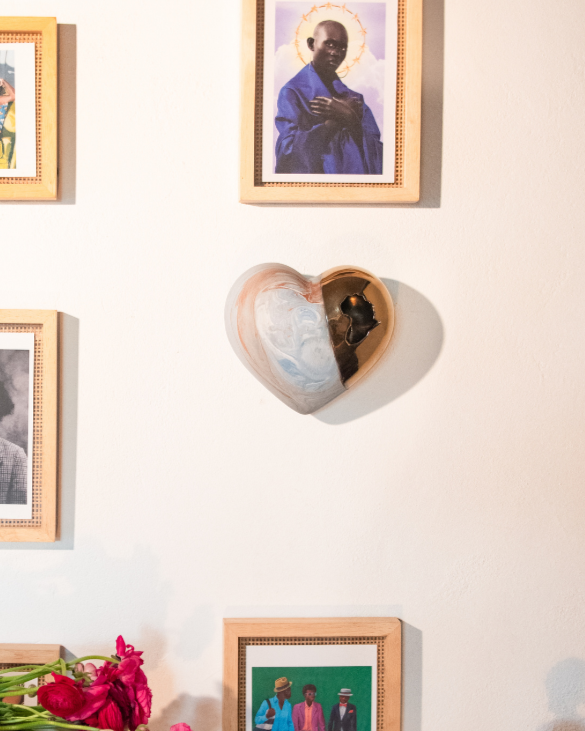 Wall with framed pictures, a heart-shaped object, and decorative items.