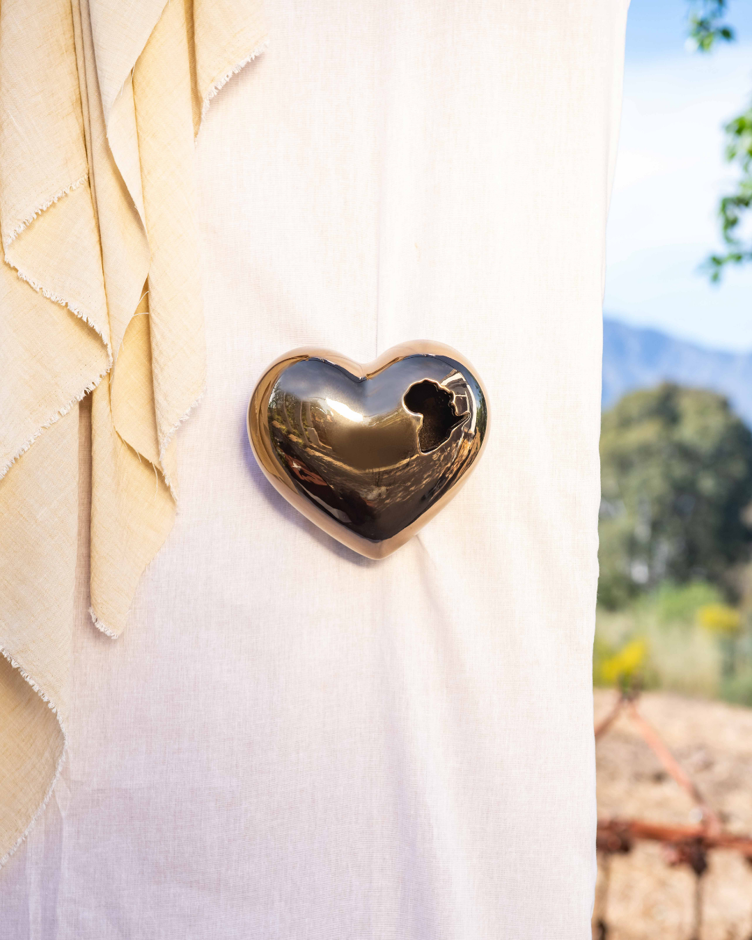 3D Heart-shaped bronze object with the African content cut out of the ceramic vessel on a white surface with a blurred natural background