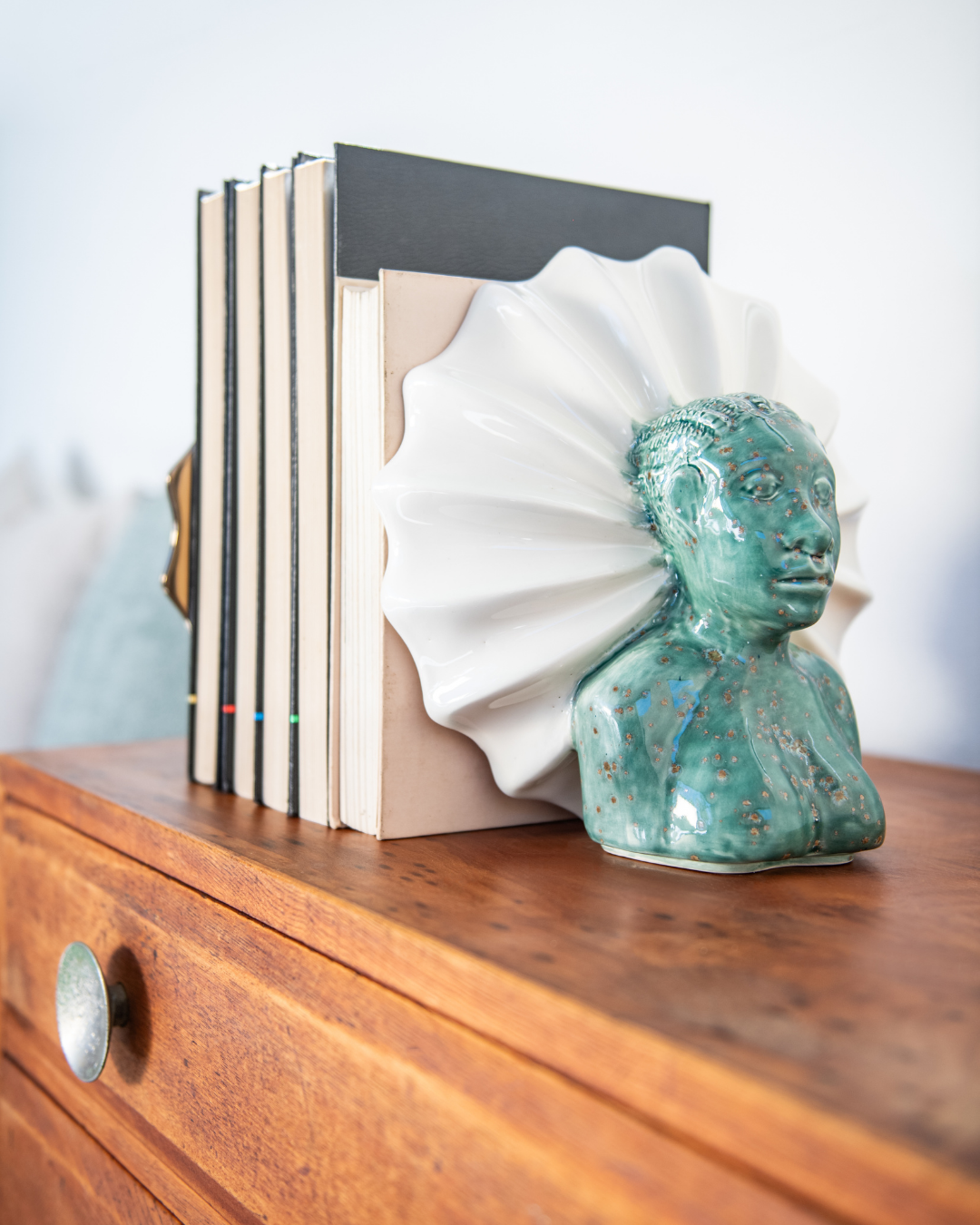 Decorative bookends on a wooden surface with a white vase in the background