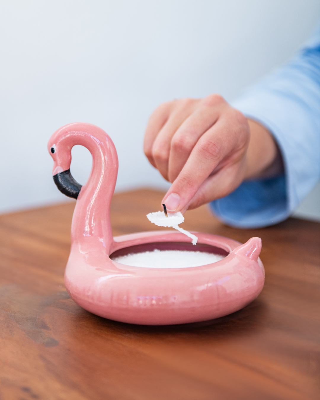Pink flamingo-shaped container with a hand on a wooden surface.