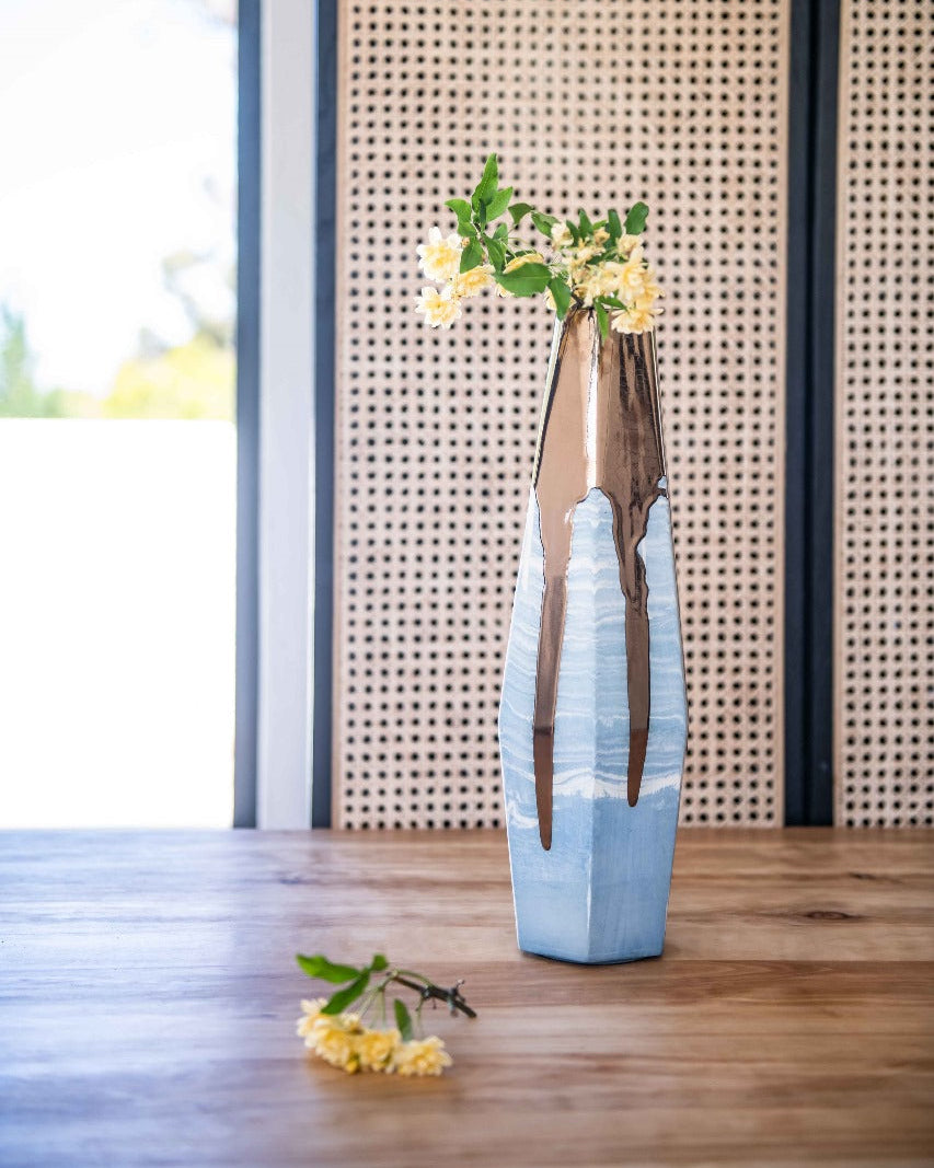 Rialheim Blue Vase with Gold dripping details on a wooden table in front of a cupboard