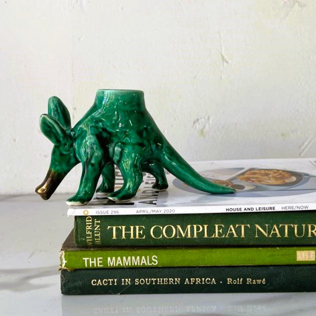 Rialheim ceramic candle holder in green emerald with black speckles on a stack of books