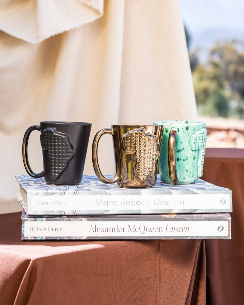 Three mugs on a stack of books with a blurred outdoor background