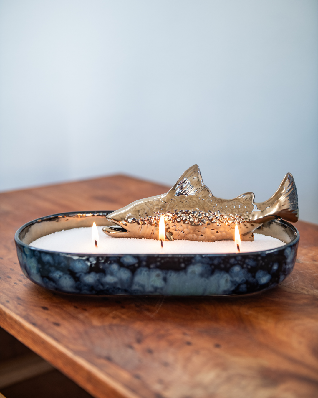 Decorative candle with a fish-shaped candle holder on a wooden surface