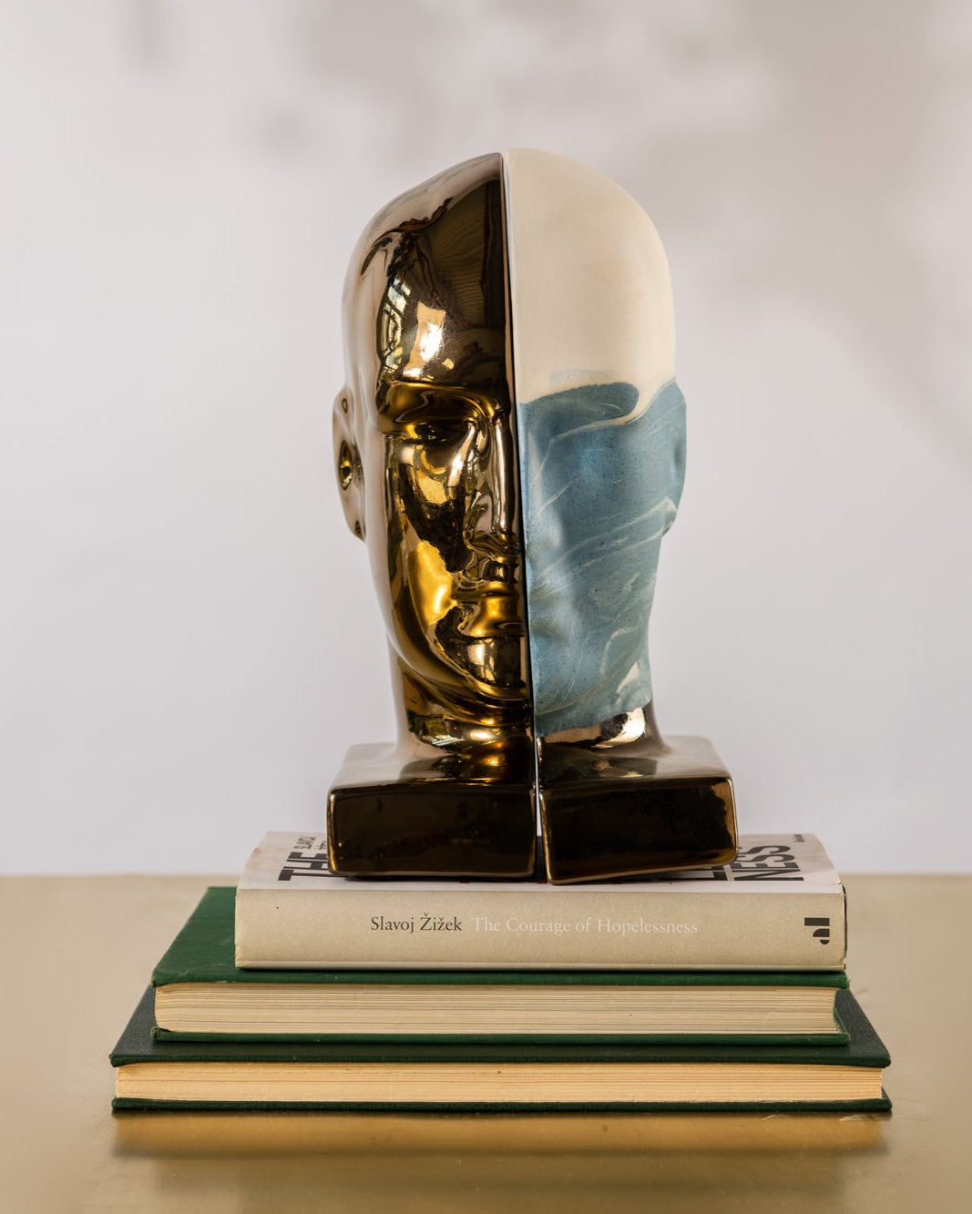 Bookend shaped like a half-human, half-beast figure on a stack of books with a plain background