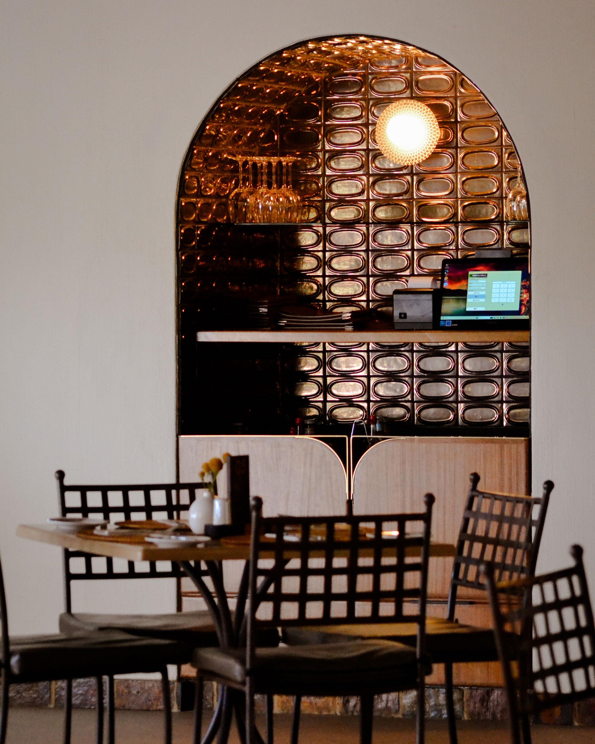Dining area with tables and chairs in a restaurant setting, featuring a decorative mirror.