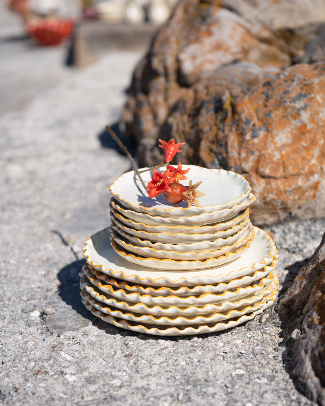 Stack of ceramic plates with floral design on a stone surface