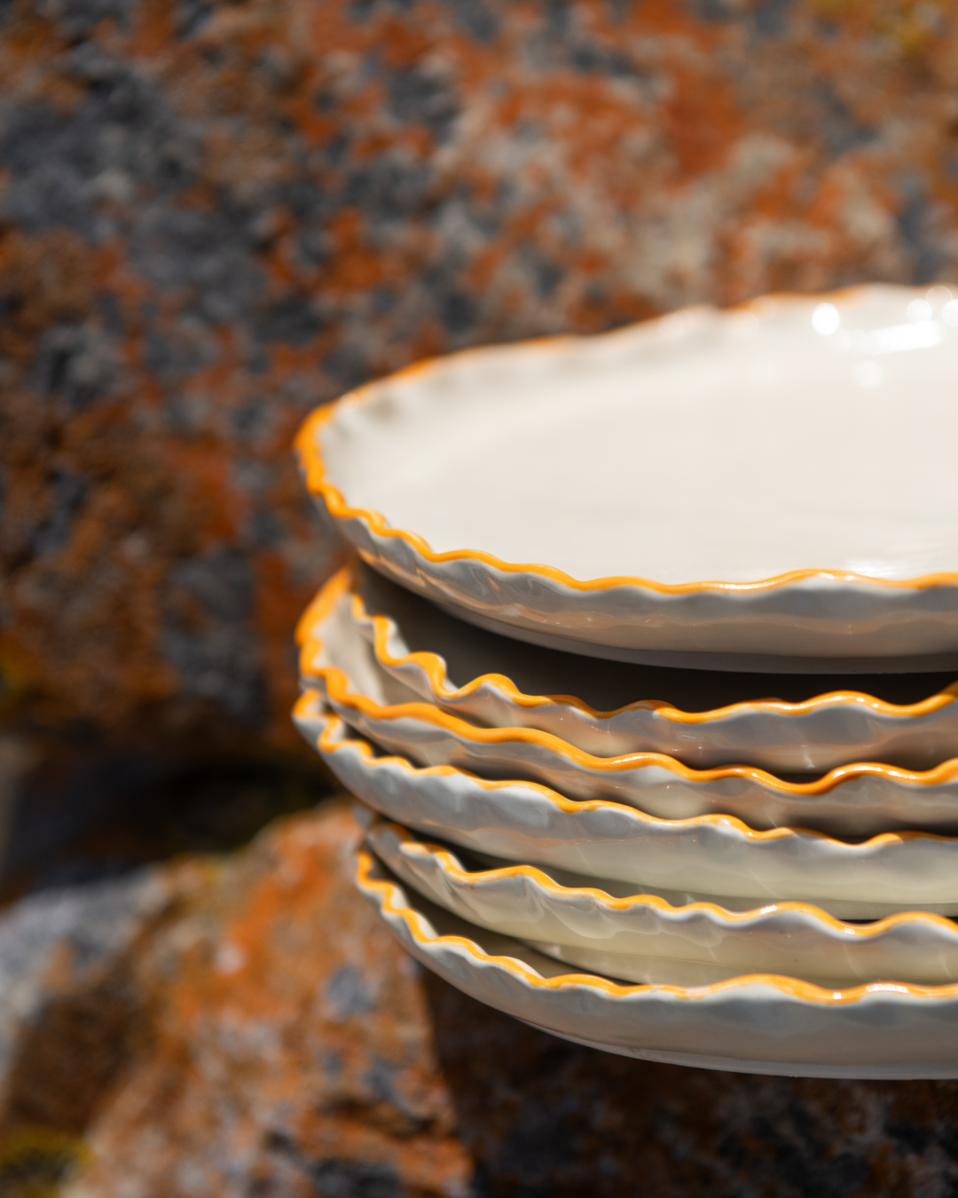 Stack of ceramic plates with scalloped edges on a textured surface