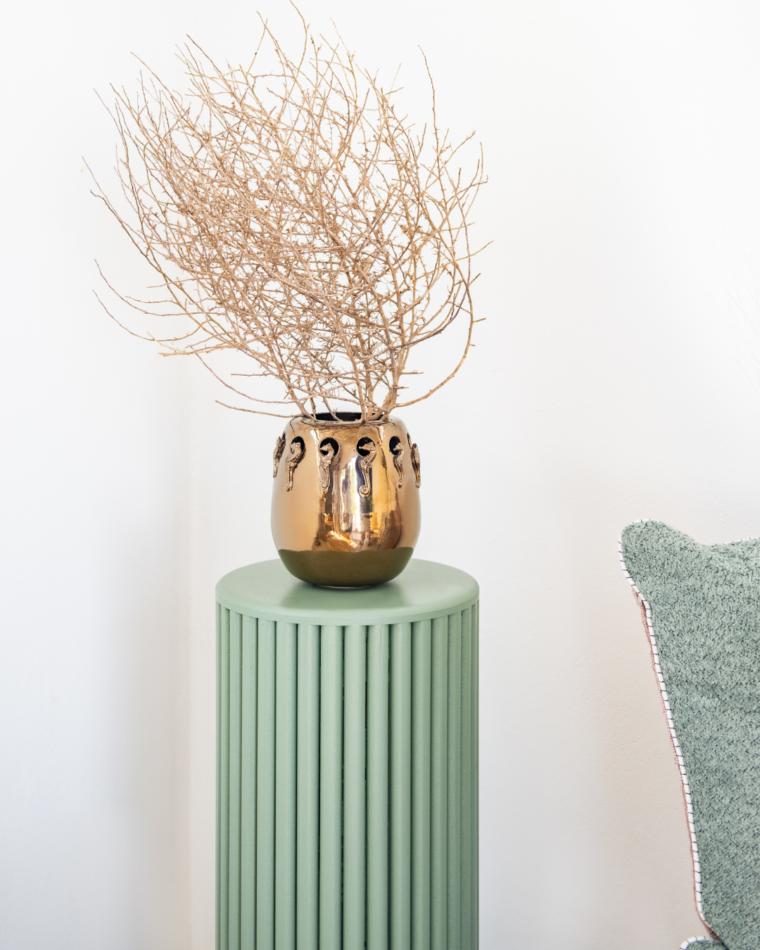 Bronze vase seahorses and with dried branches on a green pedestal against a white background