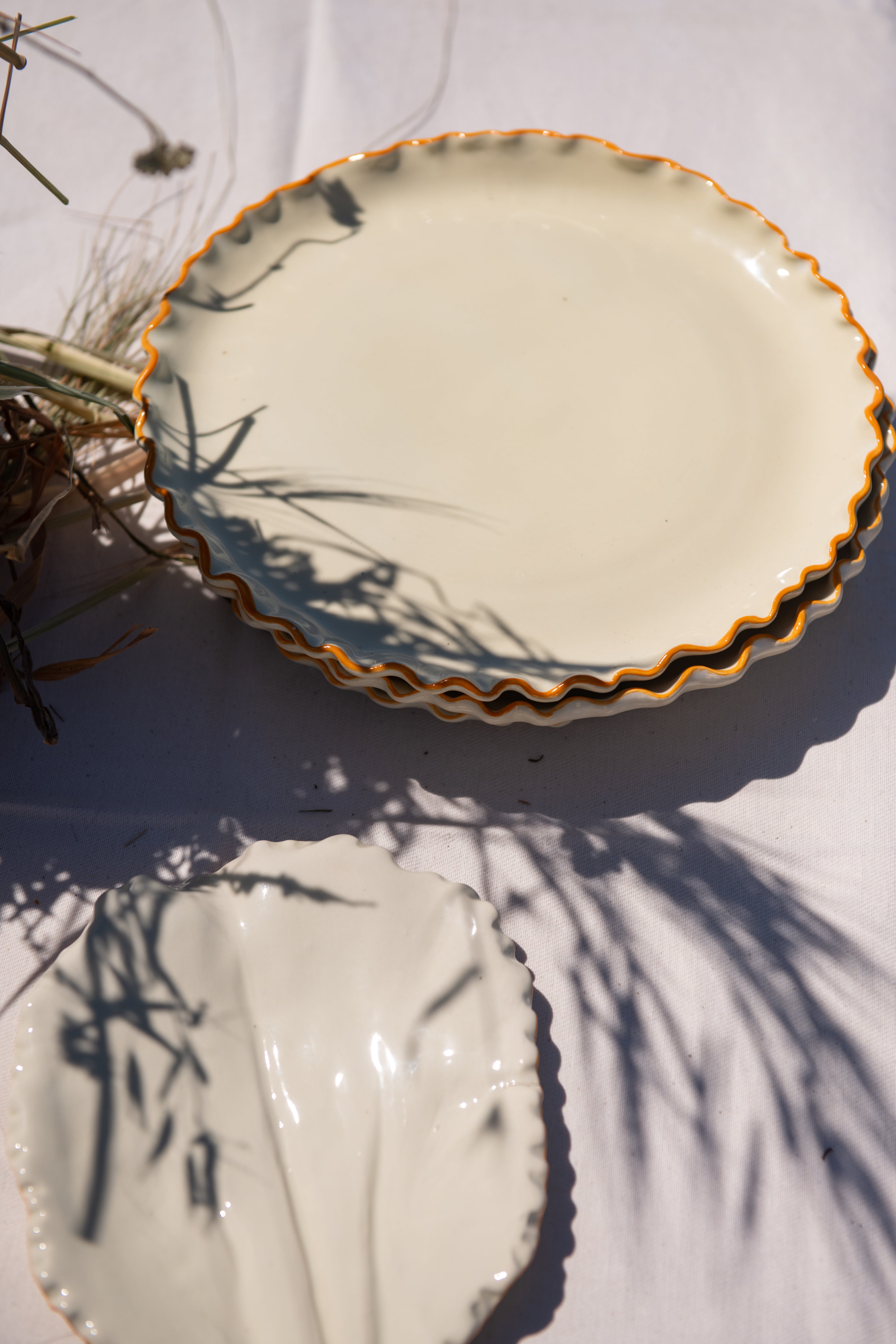 Two ceramic plates with decorative edges on a white surface with shadows.