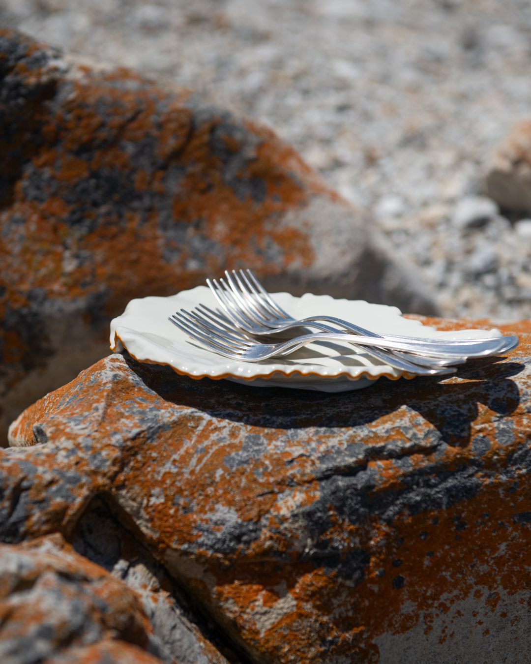 Silverware on a white plate on a textured stone surface