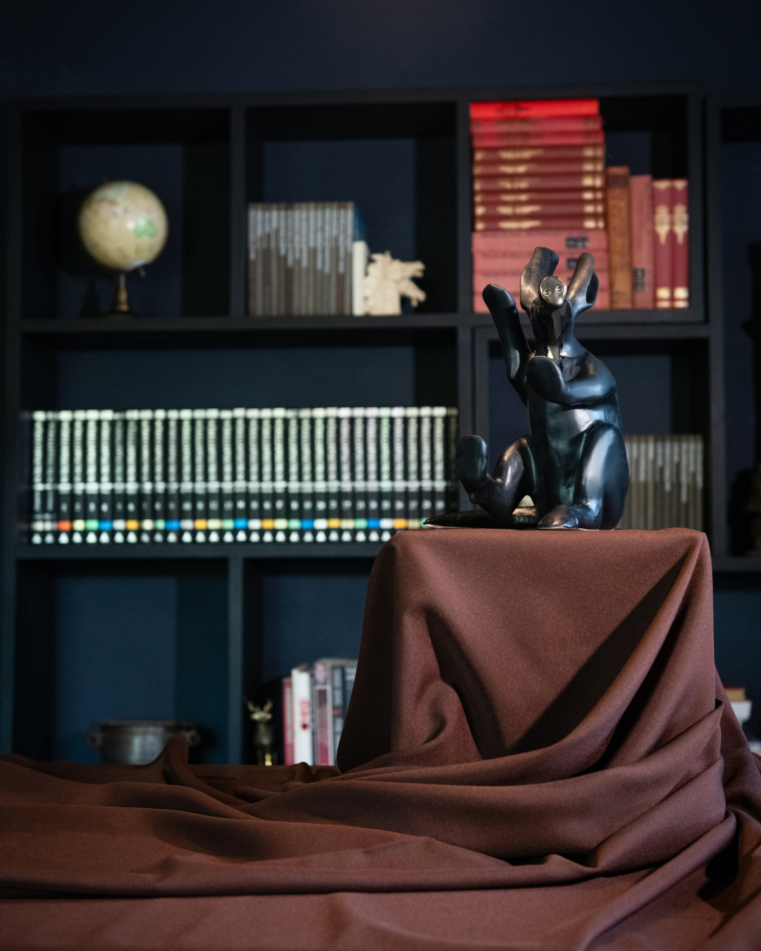 Aardvark statue on a draped surface with a bookshelf in the background