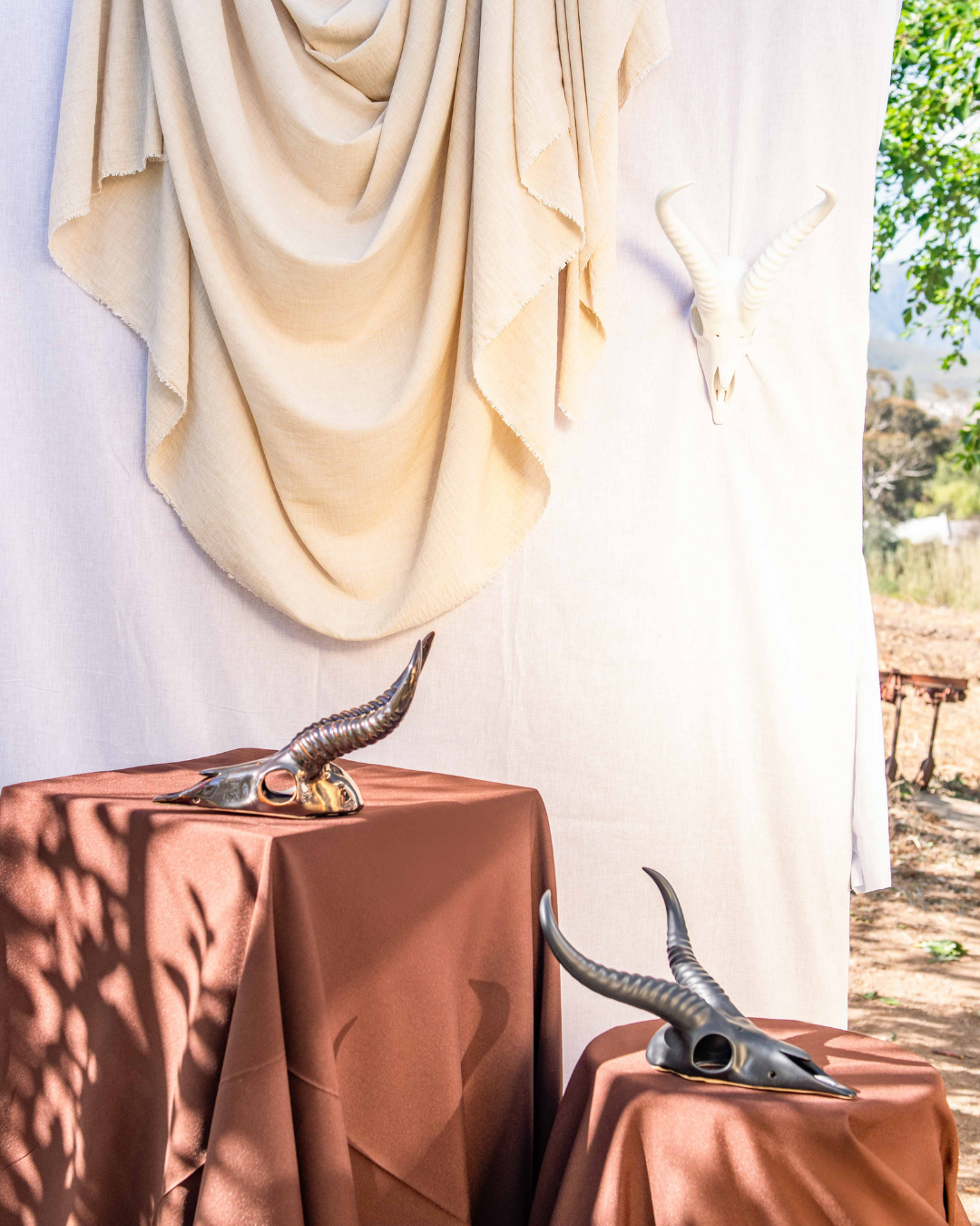 Decorative table settings with Springbok animal horns on brown tablecloths against a white draped backdrop.