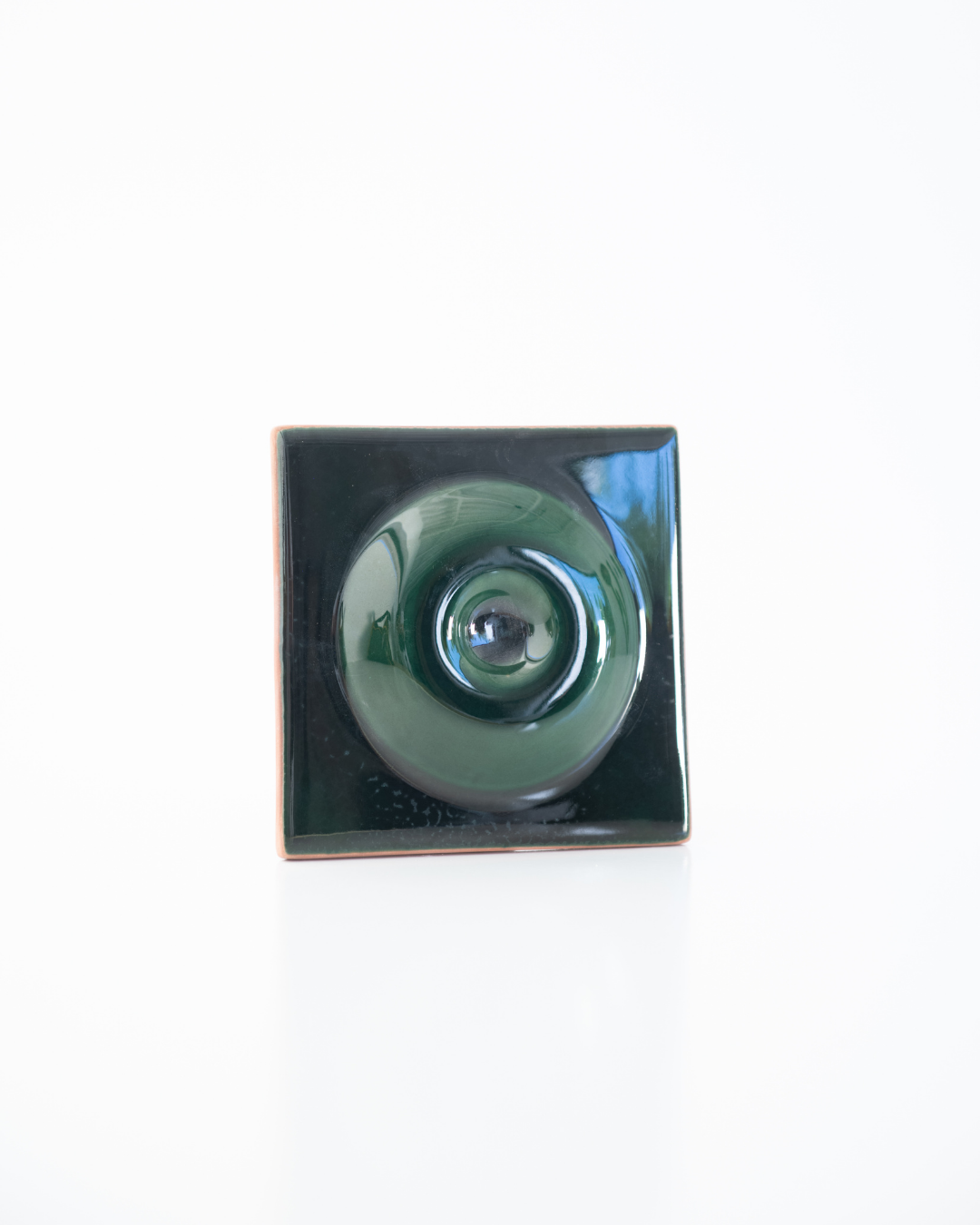 Green ceramic tile with a central circular design on a white background