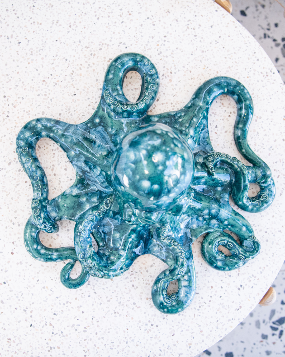 Blue ceramic octopus sculpture on a textured white surface
