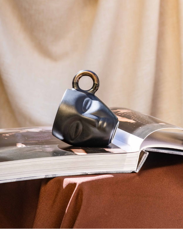 Decorative Mug on an open book with a curtain and outdoor view in the background