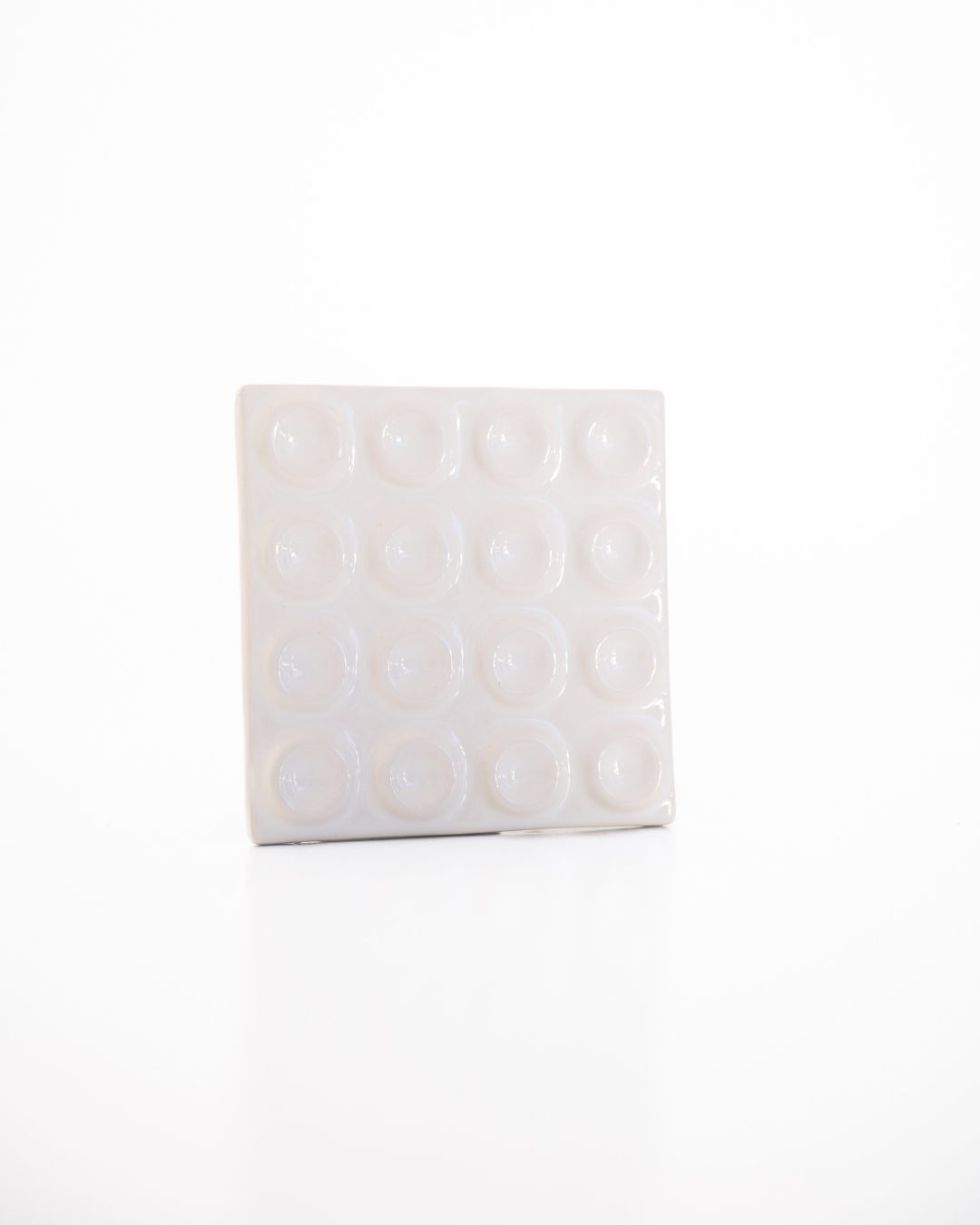 White square tile with circular patterns on a white background