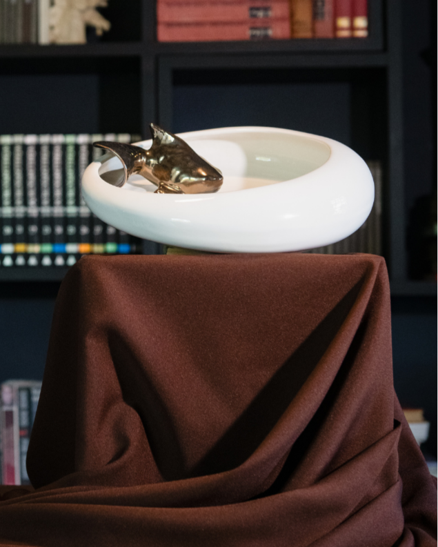 Futuristic KOI fish creature on a white platform with a dark bookshelf background