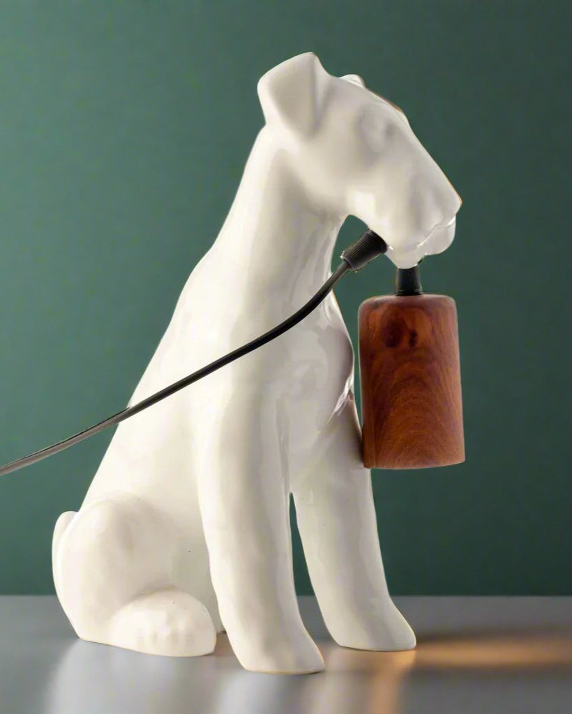A table lamp shaped like an Airedale dog holding the bulb