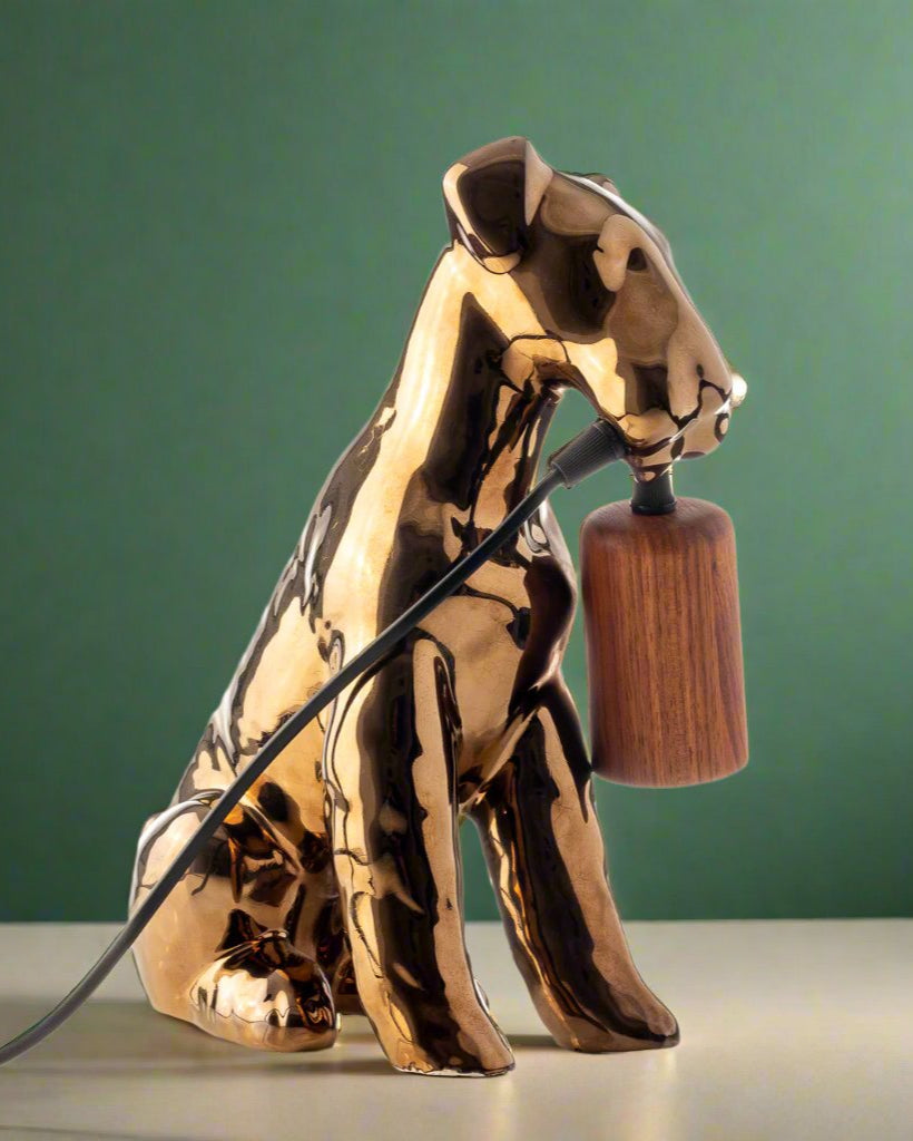 A table lamp shaped like an Airedale dog holding the bulb