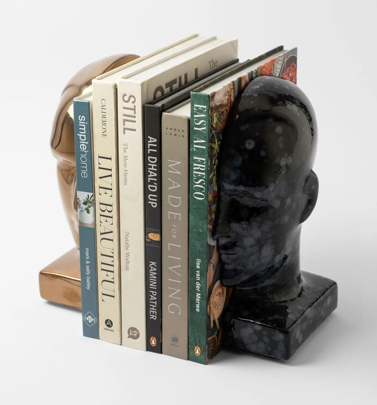 Bookends shaped like human heads holding books on a white background