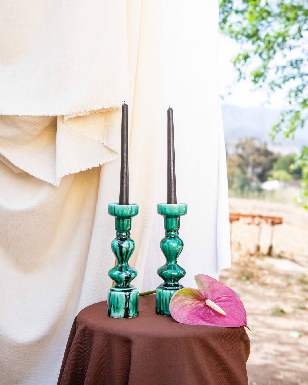 Green candle holders with black candles on a table outdoors