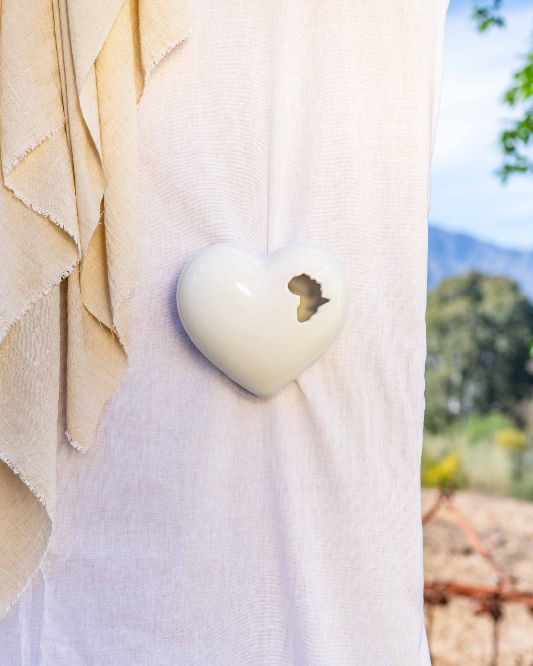 3D Heart-shaped White object with the African content cut out of the ceramic vessel on a white surface with a blurred natural background