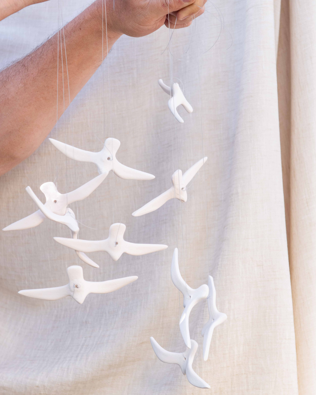 White decorative ceramic Bisque birds elements resembling birds hanging against a light background