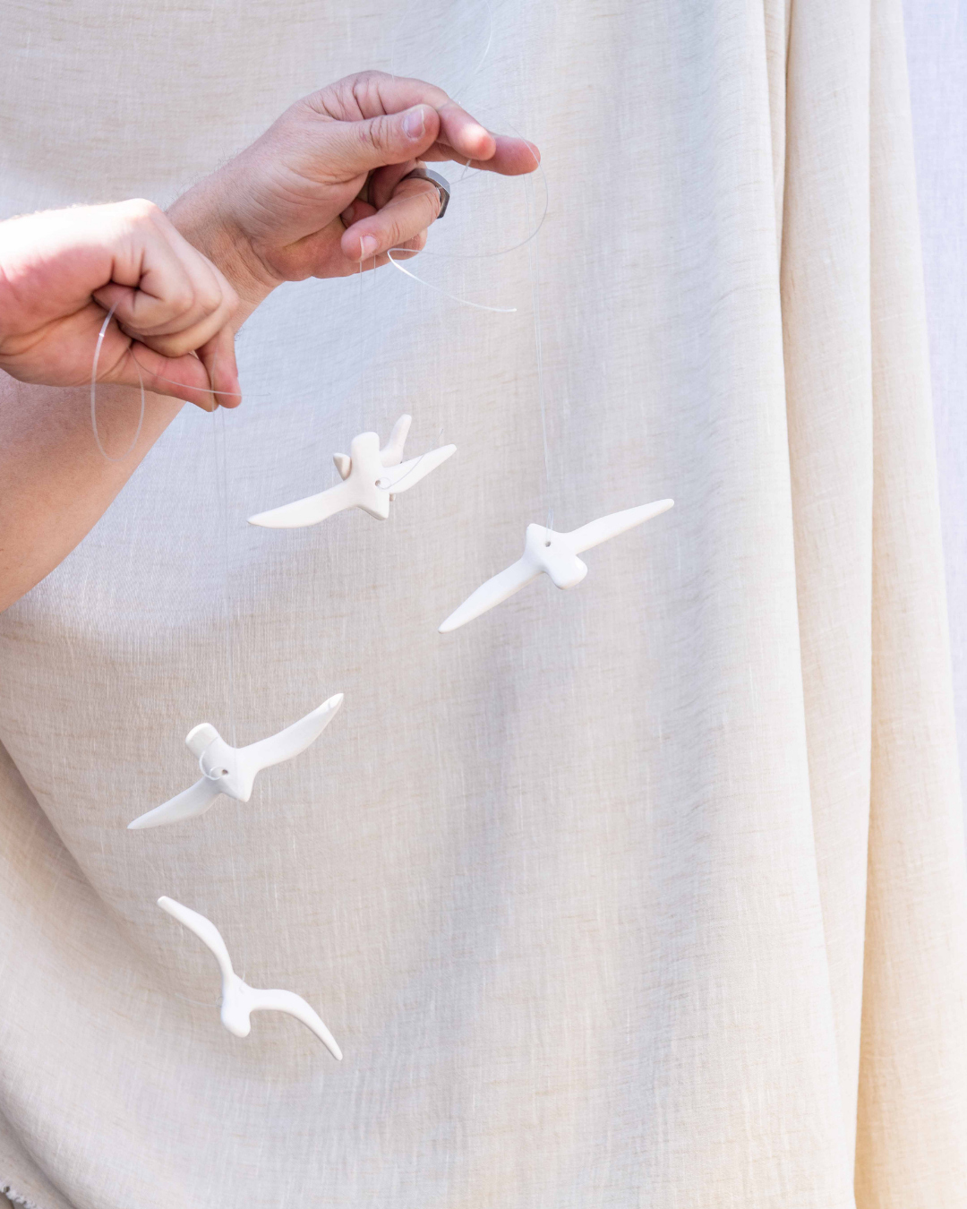 White ceramic bisque birds being held by a person against a light background