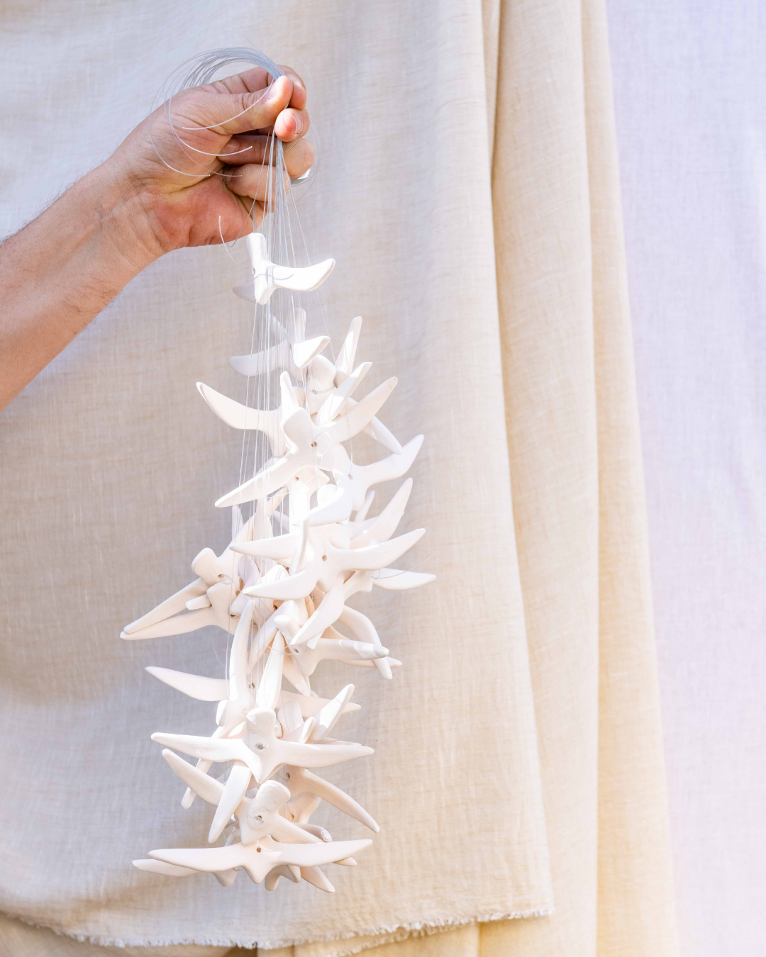 Hand holding a decorative ceramic Birds ornament against a neutral background