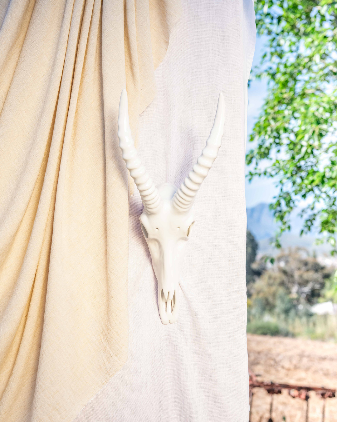 White deer statue draped with a white cloth against a blurred natural background