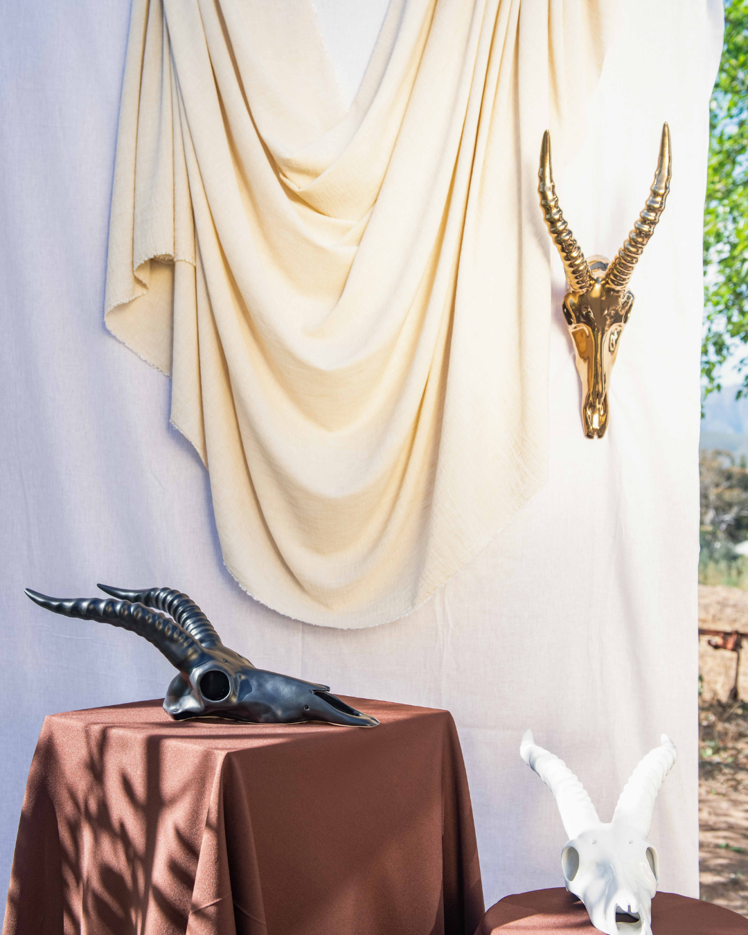 Decorative blesbok skull arrangement with animal skulls on a table against a draped fabric backdrop.