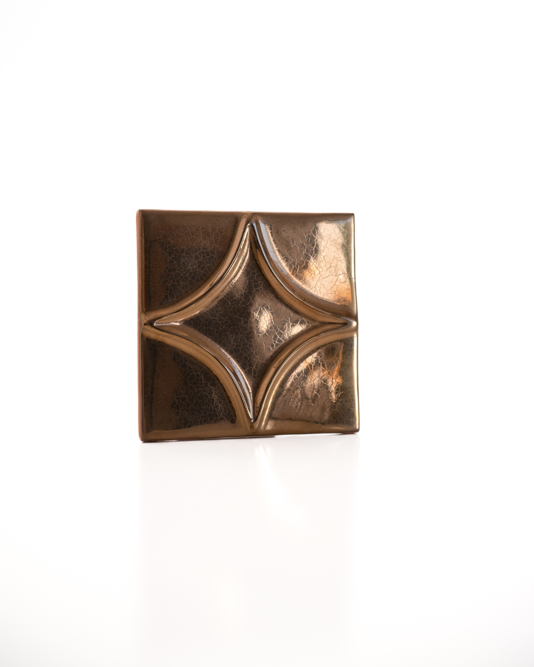 Bronze decorative square tile with intricate design on a white background