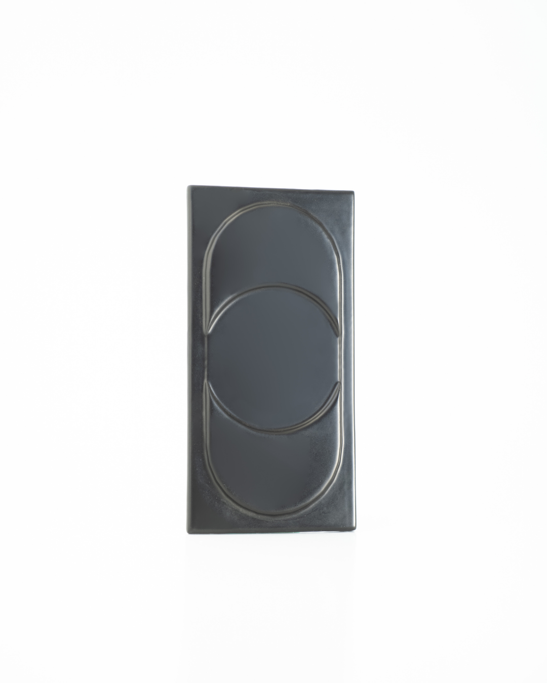 Rectangular black tile with circular design on a white background