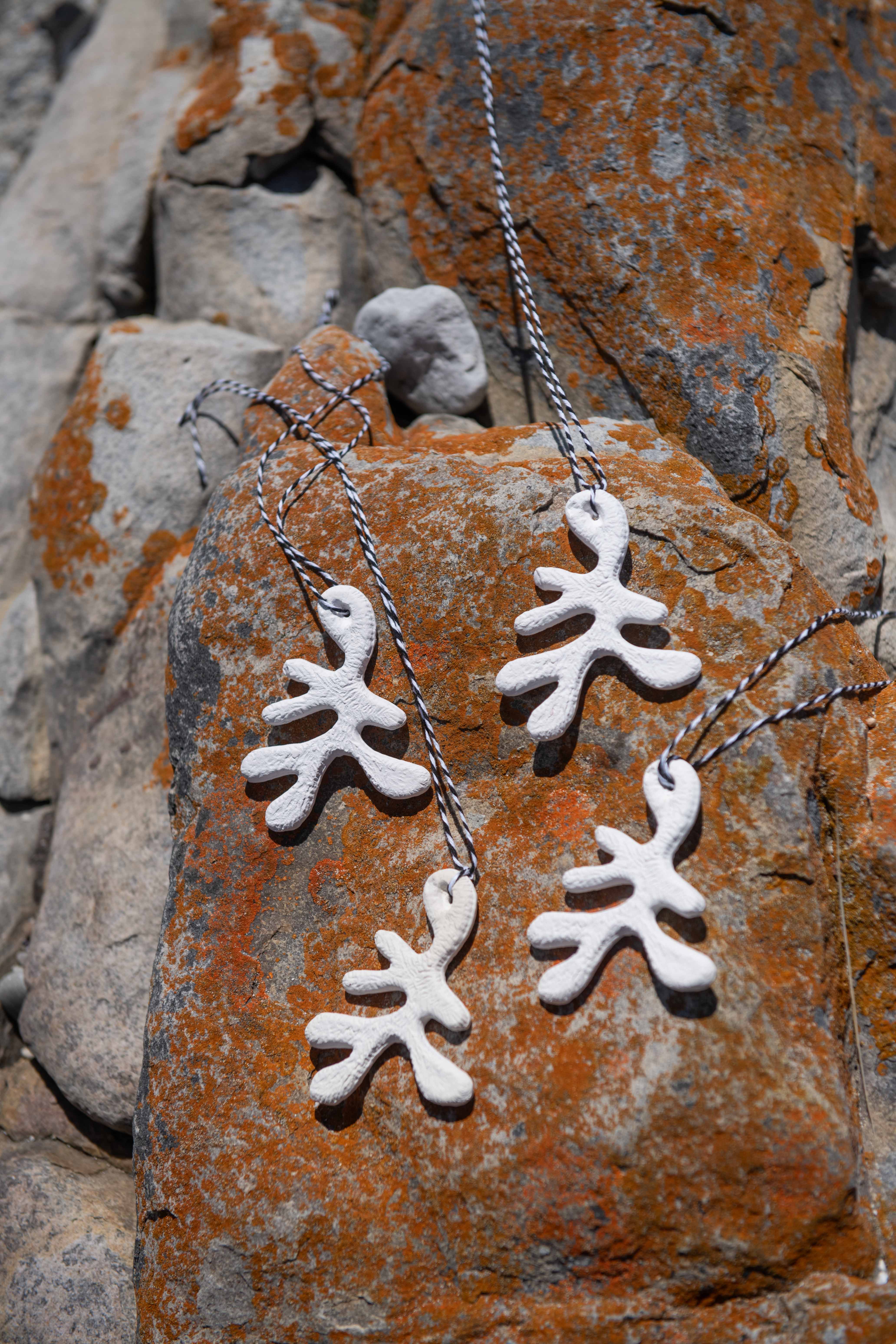 White coral-like pendants on a chain against a textured stone background