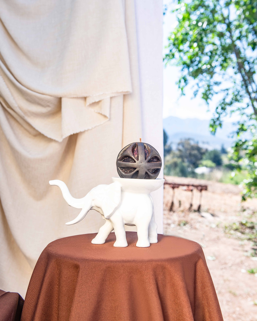 White elephant figurine on a round table with a blurred outdoor background