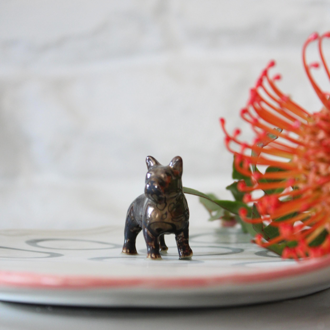 Small bronze dog figurine on a white plate 